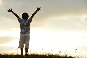 Active kid spending happy time on summer meadow by sunset