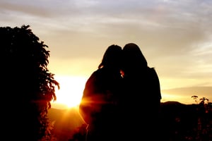 couple hugging in front of a sunset